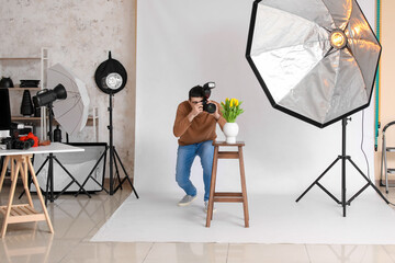 Wall Mural - Young male photographer taking picture of tulips in studio