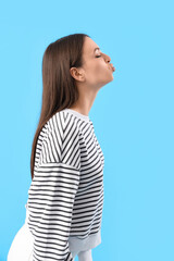 Sticker - Young woman blowing kiss on blue background