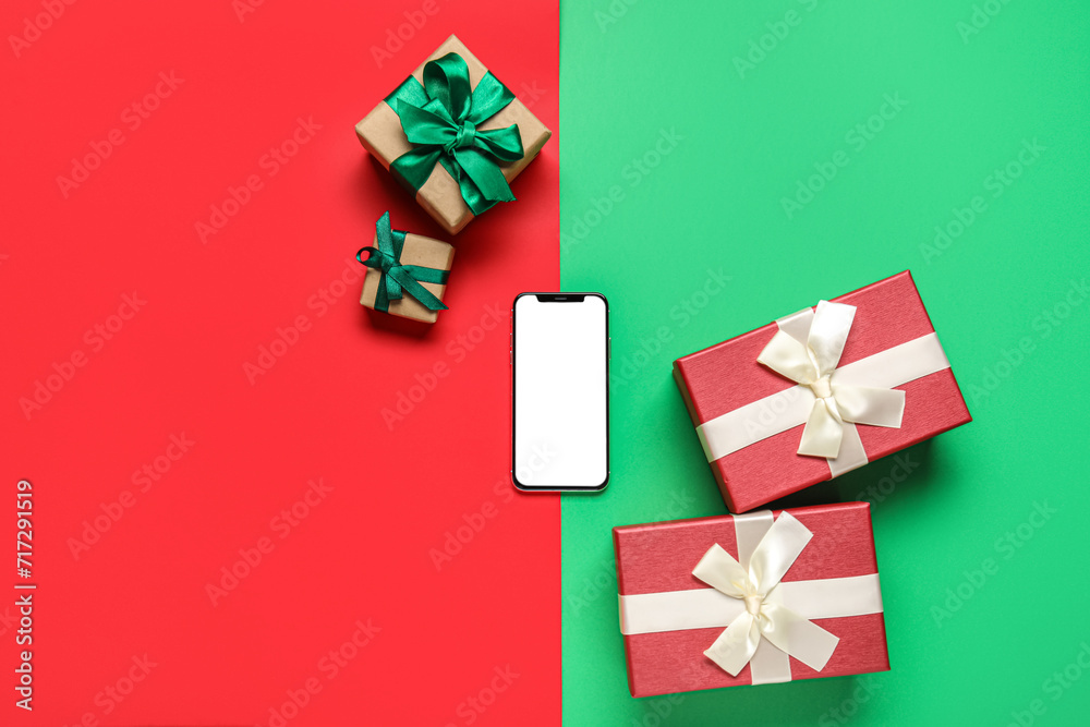 Modern mobile phone and Christmas gifts on color background
