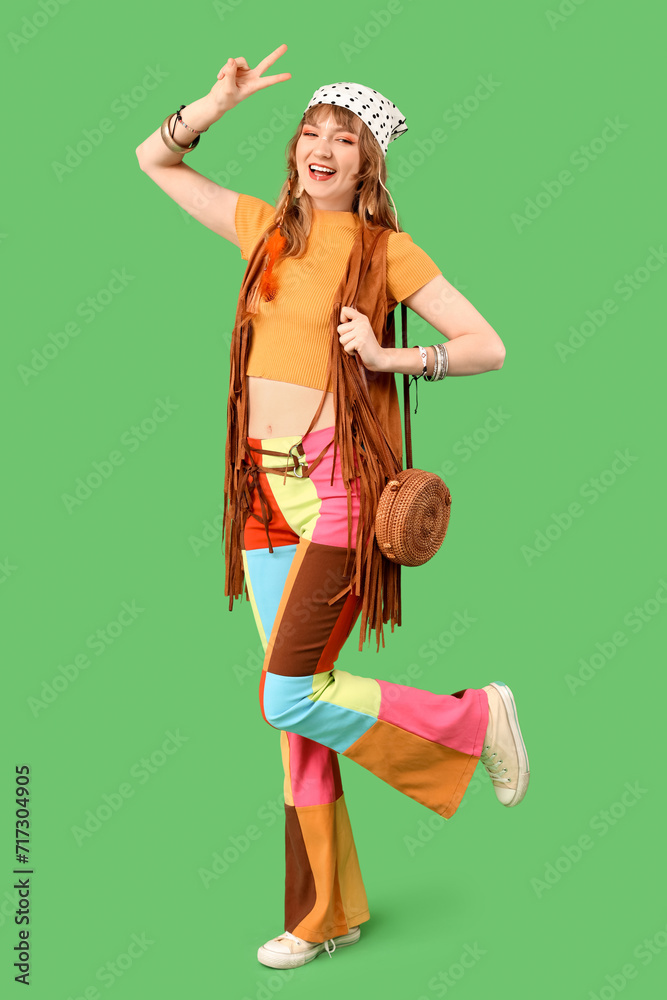 Female hippie showing victory gesture on green background