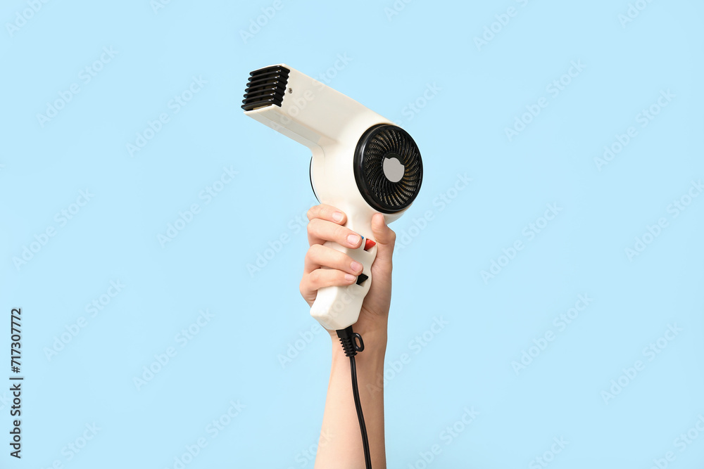Female hand with hairdryer on color background.
