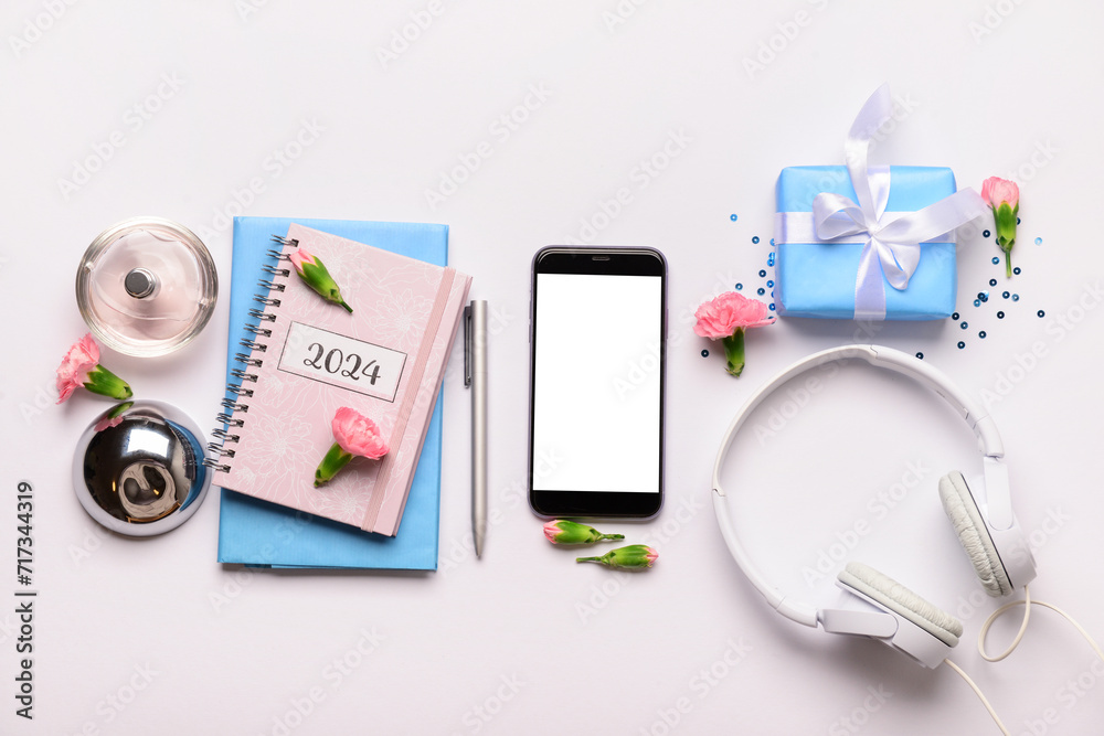Composition with modern mobile phone, notebooks, headphones and flowers on white background
