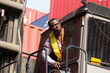 African American male container yard worker working, control container boxes on forklift truck before loading at commercial dock site. Black male people worker work at cargo freight ship