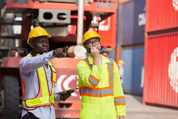 Group of diverse male container yard worker working and checking container boxes at commercial dock site. Black male and Asian male people worker inspecting container boxes from cargo freight ship