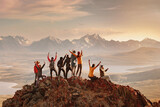 Fototapeta  - Big group of happy tourists are having fun and greeting sunset at mountain top. Active vacations concept