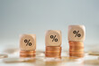 © tanoy1412 - Business and financial growth, Interest rates increase, Inflation, Sale price, budget and tax rise concept. Wooden block with percentage sign on growing of stack of money coins.