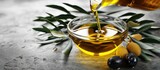 Fototapeta  - Organic olive oil pouring from glass bowl. Copy space image. Place for adding text or design