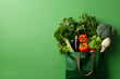 Eine Tasche voll mit verschiedenem Gemüse auf grünem Hintergrund 