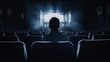Rear view of a silhouette of one person sitting in an armchair and watching a movie on a cinema screen in the dark.