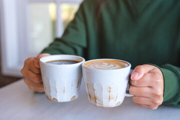 Poster - Closeup image of a woman holding and clinking two cups of hot coffee