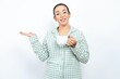 Funny Beautiful young woman wearing green plaid pyjama and holding a cup hold open palm new product great proposition