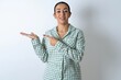 Positive Beautiful young woman wearing green plaid pyjama and holding a cup promoter point index finger copyspace hold hand demonstrate offer ads promo