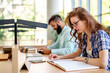 © NDABCREATIVITY - Happy group of students studying and working together in a college library