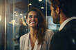 business people smiling while chatting while standing against glass wall