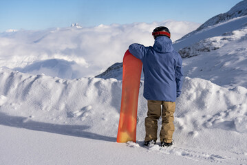 Wall Mural - Man holds a snowboard on the background of the alps. Snowboarder stands with a snowboard in the alps. Winter in french alps.