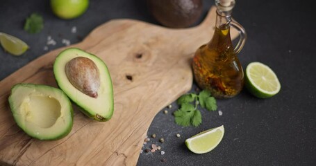 Sticker - Halved green avocado fruit on wooden cutting board at domestic kitchen