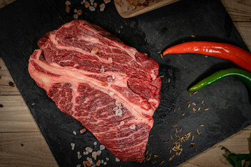 Poster - raw cowboy steak with seasonings on wooden background, prime rib eye on bone, top view