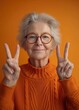 © olegganko - senior woman in glasses making a peace sign with a peace sign woman