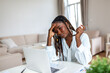 Serious frowning African American ethnicity woman sit at workplace desk looks at laptop screen read e-mail feels concerned. Bored unmotivated tired employee, problems difficulties with app