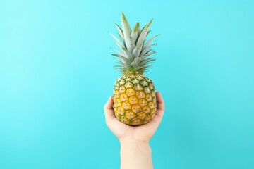 pineapple in hand on a blue background. hand holds pine apple