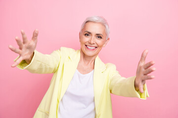 Poster - Portrait of friendly office manager mature woman in yellow suit open arms cuddles inviting to company isolated on pink color background