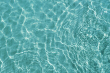 Blue Water Surface Viewed From Above In Outdoor Sea, Sun Reflection, Dimply. Surface Abstract Background. Clear Water In Sea With Ripple In Clean Aqua Liquid. Summer Wallpaper Blue Background