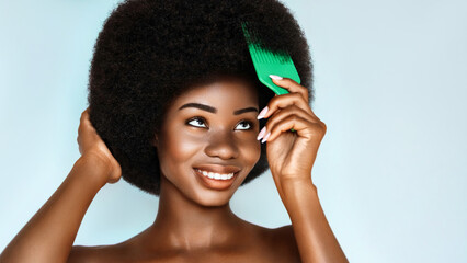 Wall Mural - curly afro hair treatment. haircare cosmetic. overjoyed african american model is brushing her hair 