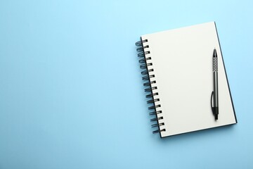 Wall Mural - Notebook and pen on light blue background, top view. Space for text