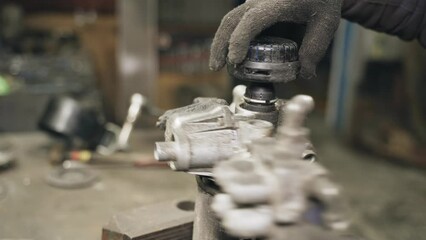 Poster - A car mechanic unscrews the filter housing clamped in a mechanical vice. Replacing the filter
