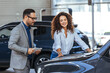 © Dragana Gordic - Salesman helping the female customer to choose a new car .  Car Sales Manager Showing Auto To Lady Buyer Standing In Luxury Automobile Dealership Store. Buying Vehicle Concept
