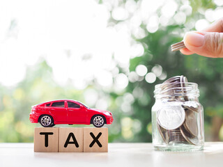 Poster - Close up hand putting coin in glass bottle, Toy car and Wooden blocks with the word TAX . The concept of saving and manage money to success transportation, Paying tax and car loan