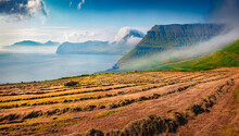 Haymaking In Faroe Islands. Misty Morning View Of Mountain Peaks. Wonderful Summer Scene Of Outskirts Of Velbastadur Village, Denmark, Europe. Beauty Of Countryside Concept Background.