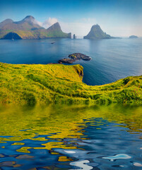 Wall Mural - Tindholmur cliffs and green pasture reflected in the calm waters of small pond. Wonderful summer view of Faroe Islands. Nice morning view of Vagar island, Denmark, Europe.