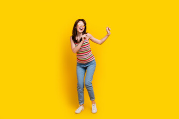 Wall Mural - Full size photo of adorable woman dressed knitwear top jeans pants in sunglass dancing at summer party isolated on yellow color background