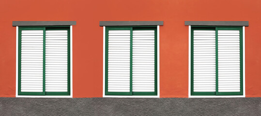 Wall Mural - Three windows in a row. House closed shutters. Window shutters background. Red home wall facade. Architecture texture. Green window frame. Wooden stripes window cover. European style panoramic design.