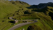 Twisty Mountain Road. An Amazing Aerial View Of A Car Driving On A Twisty Alpine Road During Golden Hour, Filmed In The Austrian Alps. Concept Of A Road Trip And Luxury Travel.