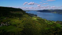 Aerial Drone Shot Over Mountain Range Covered With Green Vegetation On Both Sides Of A Fjord In Norway On A Cloudy Day.