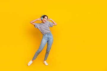 Full body photo of overjoyed young lady arms touch headphones dance empty space ad isolated on yellow color background