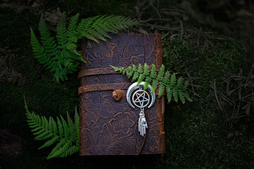 Sticker - magic witch book and wiccan amulet with pentagram in forest, natural dark abstract background. Esoteric Ritual, witchcraft, spiritual practice. Mysticism, modern wicca occultism concept. top view