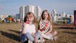 Two little girls sisters sit on the lawn in the city in the summer and eat delicious ice cream