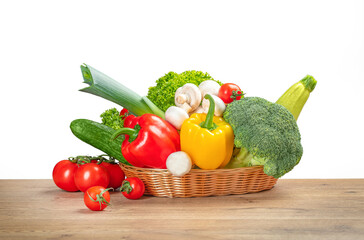 Wall Mural - Basket with fresh vegetables and mushrooms on wooden table isolated on white, Concept healthy and balanced eating