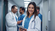 © MP Studio - Smiling young female doctor with a stethoscope around her neck, holding a tablet, standing in a hospital corridor.