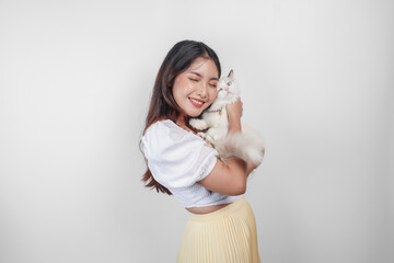 Wall Mural - Portrait of young Asian woman holding cute ragdoll cat with blue eyes. Female hugging her cute long hair kitty isolated by white background. Adorable domestic pet concept.