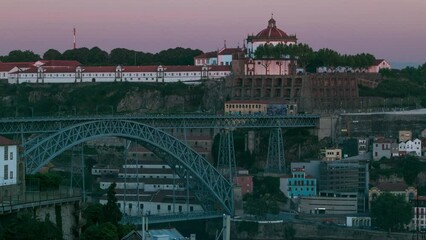 Wall Mural - Sunset time, shadow covering Douro riverside with the Dom Luiz bridge and Mosteiro da Serra do Pilar, Porto timelapse, Portugal. Warm evening light