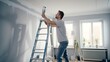 A humorous man is painting the wall in his new apartment renovation to redecorate and repair it.