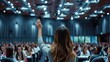 woman raises her hand to ask a question during a conference (academic or business)