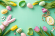 Festive Easter delights scene: top view of vibrant eggs, bunny figurine, assorted cookie cutters, themed decor and tulips on teal backdrop. Ample space for text or promotions