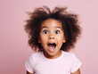 Surprised African American little girl on pink background.