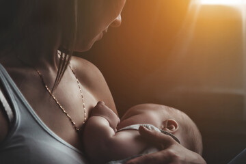 Wall Mural - Closeup mom breastfeeding newborn baby at home. Woman nursing baby in living room. Care mother spends her time caring for newborn child. Concept of motherhood and happy family. Copy space