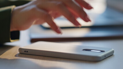 Wall Mural - unknown woman taking smartphone lying desk close up. hand holding telephone
